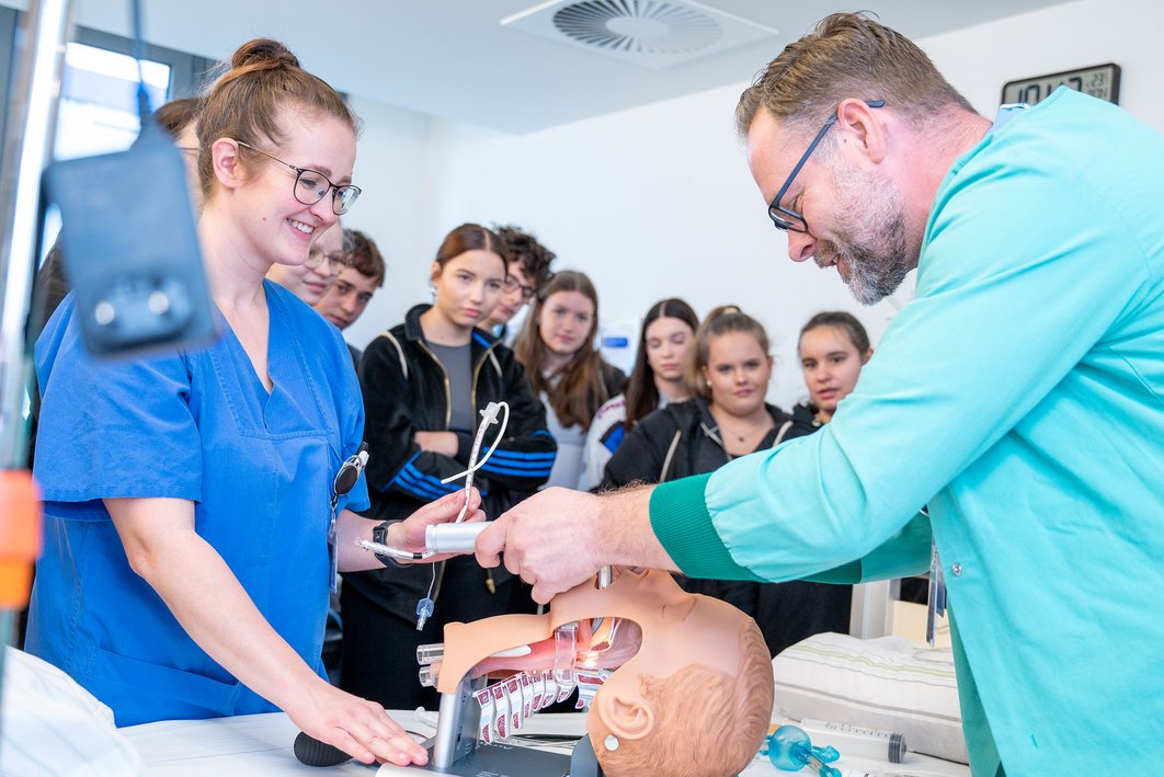„Girls' und Boys' Day - Zukunftstag“ der Universitätsmedizin Halle: Schüler:innen üben auf der Intensivstation an einer Puppe eine Intubation. Ein Arzt leitet sie dabei an.